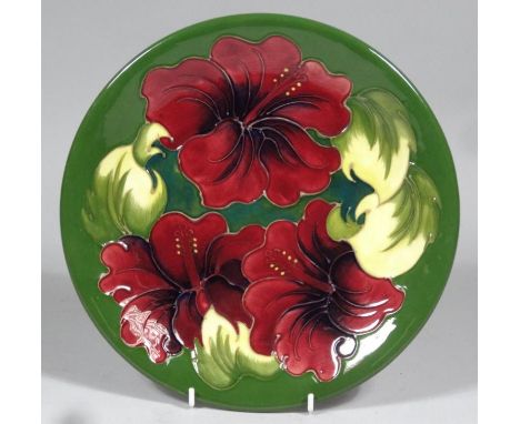 A 20thC Moorcroft plate, on green ground, tube lined flowers, in pressed and painted W M mark beneath, 26cm diameter.