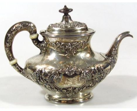 A 20thC sterling silver English teapot, of compressed form, repoussé decorated with scrolls and flower heads, with shaped spo