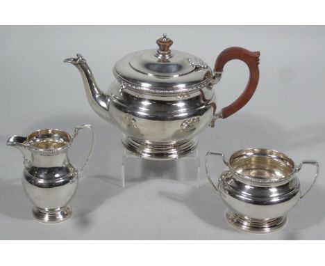 A George VI silver three piece tea set, comprising teapot, 18cm high, of compressed circular form with polished mahogany knop