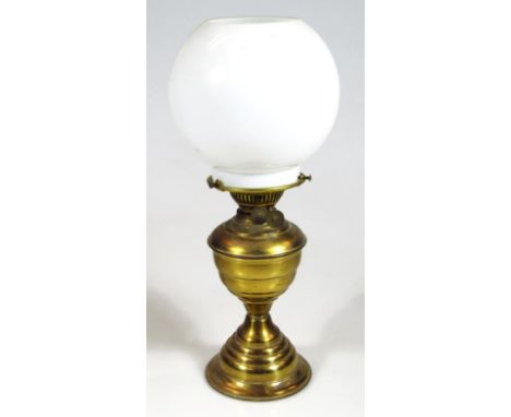 An early 20thC brass milk and clear glass oil lamp, with globular shade cylindrical funnel and shaped stem, on stepped circul