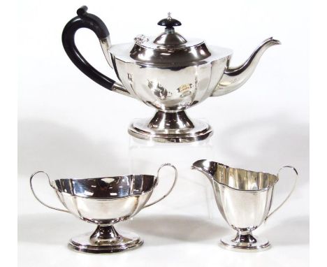 A George V silver three piece tea service, comprising teapot, 18cm high, helmet shaped cream jug and two handled sugar bowl, 