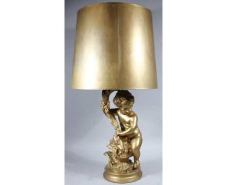 A Baroque style plaster finish gilt cherubic lamp, he sat holding an entwined scroll stem, on an inverted circular base, with