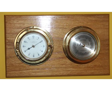 A modern wall hanging barometer and thermometer, on a lightwood background, 37cm wide.