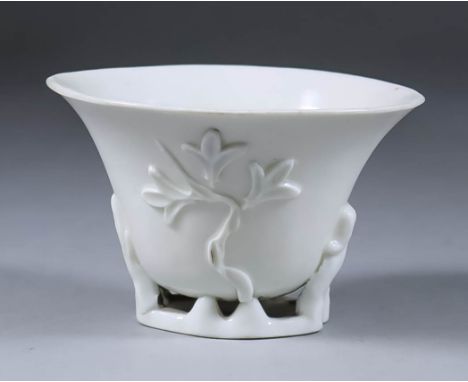 A Chinese Blanc de Chine Porcelain Dehua Libation Cup, Kangxi, 17th Century, the sides moulded with prunus blossom and magnol