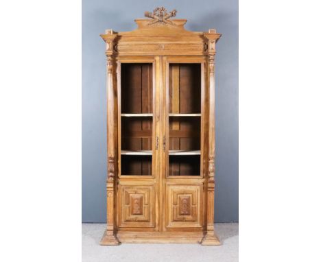 A 19th Century French Walnut Display Armoire, the moulded cornice with shaped pediment with carved ribbon, bow and arrow and 