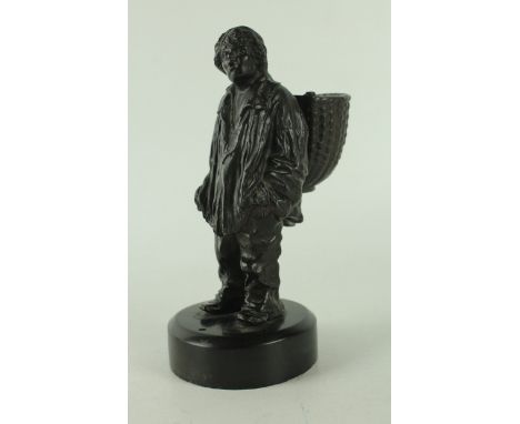 A late 19th/early 20th Century bronze figureModelled in the form of a man wearing an overcoat with a basket on his back, rais