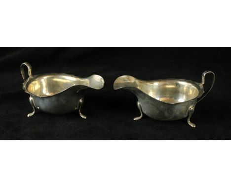A pair of silver sauce boatsWith wavy rims, raised on three feet with loop handles, by Viner's Ltd., London 1935, length 14.5