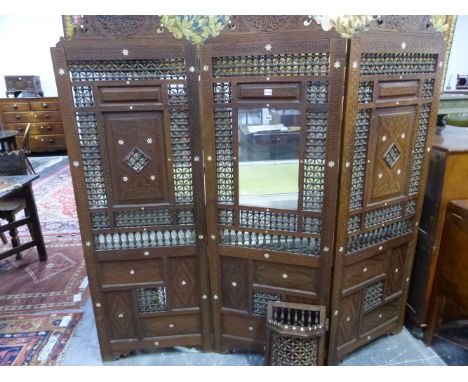 AN EARLY 20th C. MIDDLE EASTERN HARDWOOD THREE FOLD SCREEN, THE ARCHED TOP TO EACH PANEL INLAID WITH A MOTHER OF PEARL FLOWER