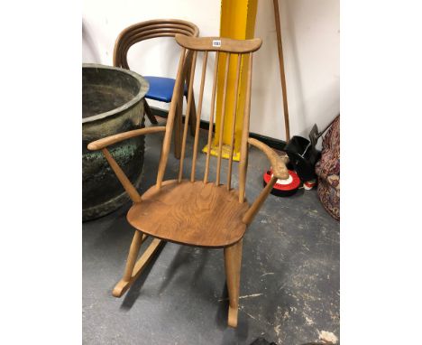 AN ERCOL ROCKING CHAIR WITH WAVY TOP RAIL, FIVE STICK BACK CURVED ARMS AND SADDLE SEAT