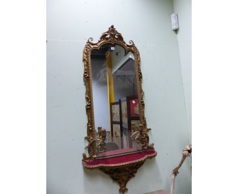 AN OGEE ARCHED GIRANDOLE WITH TWO CANDLESTICKS ABOVE A RED VELVET SHELF, THE GILT FRAME WITH FOLIAGE. 155 x 69cms.