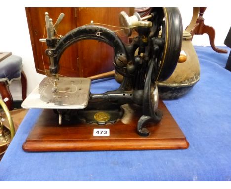 A WILLCOX AND GIBBS SEWING MACHINE WITH MAHOGANY TRANSIT CASE, A LARGE BRASS KETTLE, AND A COPPER SERVING LADLE.