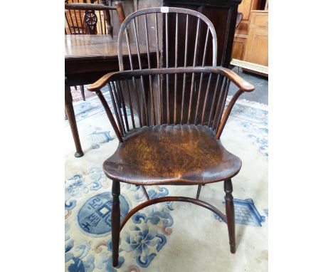 AN ANTIQUE LOW BACKED WINDSOR CHAIR WITH NINE STICK BACK, THE SADDLE SEAT ABOVE A CRINOLINE STRETCHER