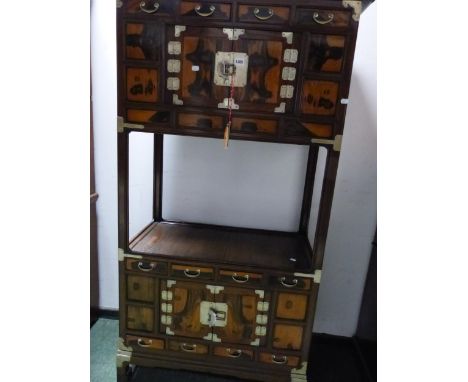A KORAN HARDWOOD CABINET WITH A CENTRAL SHELF BETWEEN CUPBOARDS EACH TOPPED BY THREE DRAWERS AND ON SQUARE SECTION SCROLL LEG