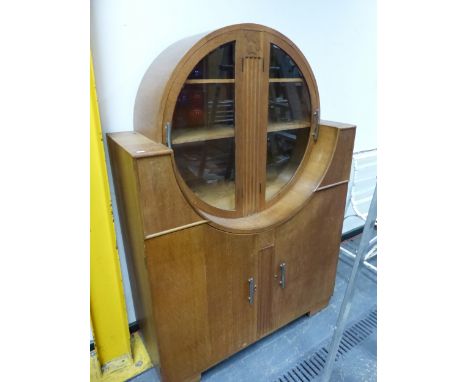 AN ART DECO OAK CABINET, THE TWO DOORS TO THE CIRCULAR TOP GLAZED OVER SHELVES, A FLUTED BAND BETWEEN THE CHROME HANDLED DOOR