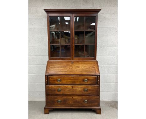 A Georgian mahogany bureau bookcase having a moulded cornice above two glazed cabinet doors and three adjustable shelves, the
