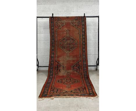 A 19th century Persian Lora runner having two central diamond lozenge medallions over an iron red abrash ground within multip