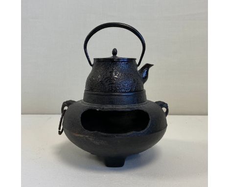 A 19th century Japanese cast iron Tetsubin or kettle having an arched swing handle over a shaped conical lidded body cast wit