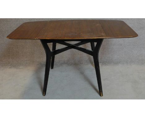 A vintage 1970's teak drop flap dining table on ebonised splay supports. 75x138x81cm 