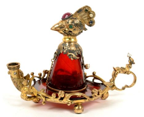AN UNUSUAL CONTINENTAL JEWELLED GILTMETAL MOUNTED RUBY GLASS INKWELL IN THE FORM OF A BIRD WITH CARYATID HANDLES AND TAPER HO