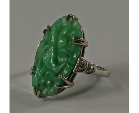 An Art Deco jadite ring, of oval form, carved with bird and flowers, with diamond set shoulders, approx. size K/L, approx 4.3