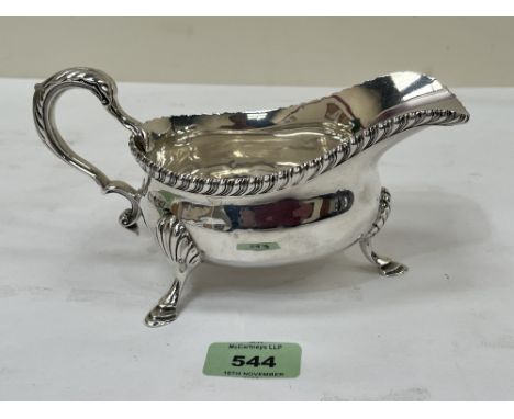 A George V silver sauce boat with scrolled handle on three shell moulded feet. Sheffield 1923. 7¾" long over handle. 11ozs 16