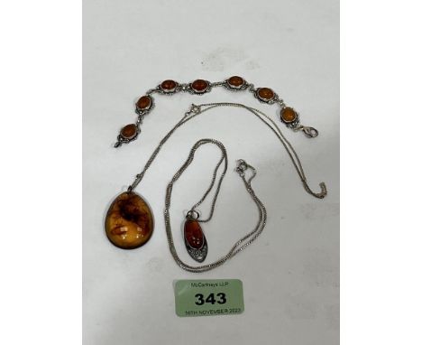 A silver and amber cabochon bracelet and two silver and amber pendants on necklet chains.