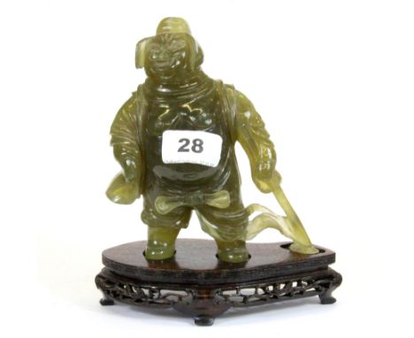 A Chinese olive green jade figure of 'Pig' from the monkey king legend standing on a carved wooden base, H. 18cm. Prov. Daphn