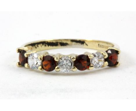 A 9ct yellow gold garnet and white stone set half eternity ring, (O).