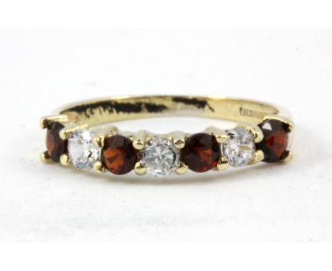 A 9ct yellow gold garnet and white stone set half eternity ring, (O).