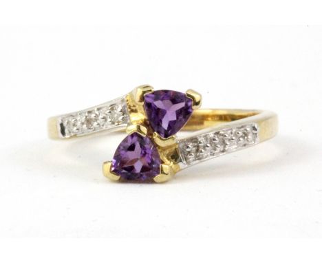 A 9ct yellow gold (stamped 375) amethyst and diamond set crossover ring, (L.5).