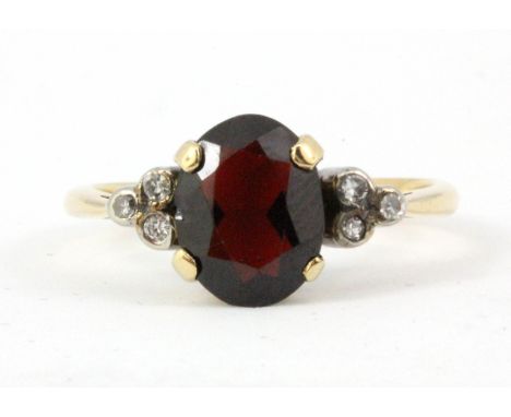 An 18ct yellow gold (worn mark 18ct) ring set with an oval cut garnet and diamonds, (K).