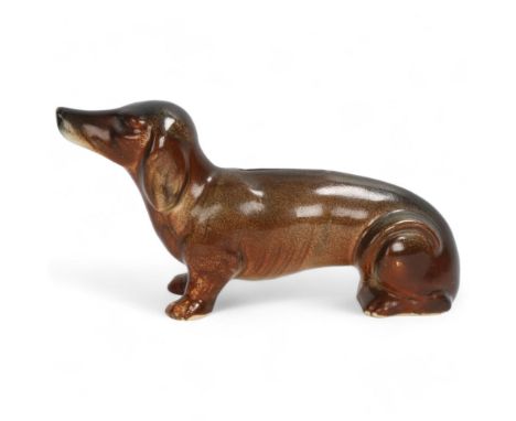 A ceramic Austrian figurine of a Daschund as a money box, shaded brown glaze, base stamped Austria, height 10cms, length 18cm