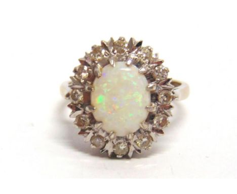 AN OPAL AND DIAMOND 18 CARAT WHITE GOLD CLUSTER RING the oval shallow cabochon approximately 10.9 by 8.6 by 3mm deep, enclose