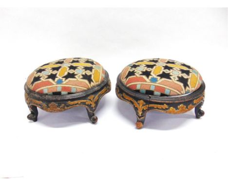 A PAIR OF VICTORIAN FOOT STOOLS the circular cushions with tapestry upholstery, on ebonised and parcel gilt bases, 34cm diame