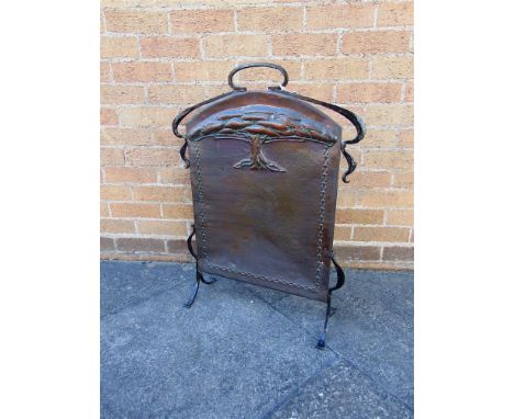 AN ARTS AND CRAFTS WROUGHT IRON AND COPPER FIRESCREEN with embossed decoration of a stylised tree, 59cm wide 78cm high
