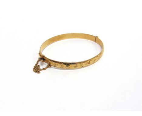 A 9 CARAT GOLD HINGED BANGLE with half engraved decoration, 6.4mm wide, 6cm internal diameter, 14.7g gross