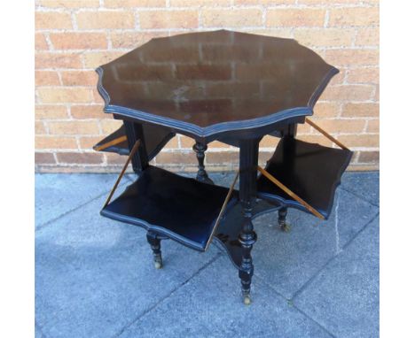 A LATE VICTORIAN/EDWARDIAN EBONISED OCCASIONAL TABLE with shaped octagonal top, and with four folding side shelves, the four 