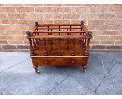 A VICTORIAN WALNUT THREE DIVISION CANTERBURY fitted with drawer on turned supports with ceramic casters