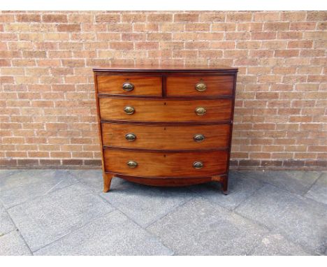 A GEORGIAN MAHOGANY BOW FRONT CHEST of two short and three long graduated drawers with brass loop handles and on out-swept fr