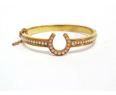 A VICTORIAN SEED PEARL AND CORAL HINGED GOLD BANGLE unmarked, the horse shoe coral set motif between a row of seed pearls, in