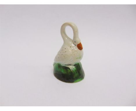 AN INTERESTING POLYCHROME GLAZED CERAMIC FIGURE modelled as a swan with stylised ring neck seated on a brown and green mound 