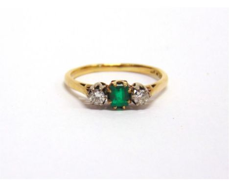 AN EMERALD AND DIAMOND THREE STONE RING stamped '18ct' and 'Plat', the square cut emerald flanked either side by brilliant cu