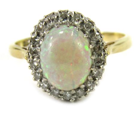 An Elizabeth II 18ct gold opal and diamond dress ring, the oval cabochon opal in claw setting surrounded by tiny diamonds, on