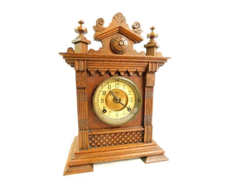 An early 20thC oak cased American mantel clock, the brass circular dial with brass chapter ring bearing Arabic numerals, with