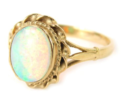 A 9ct gold opal dress ring, the oval opal in a rub over setting with twist outer border, on V splayed shoulders, Birmingham 1