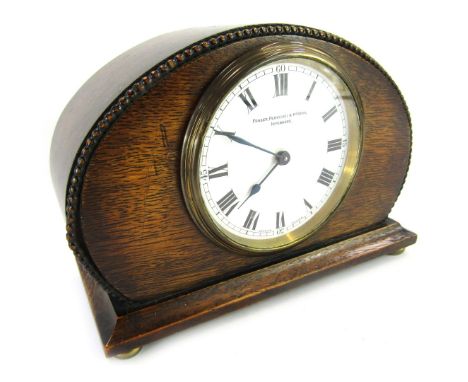 An early 20thC oak cased mantel clock, the circular white enamel dial bearing Roman numerals for Fraser, Ferguson and McBean 