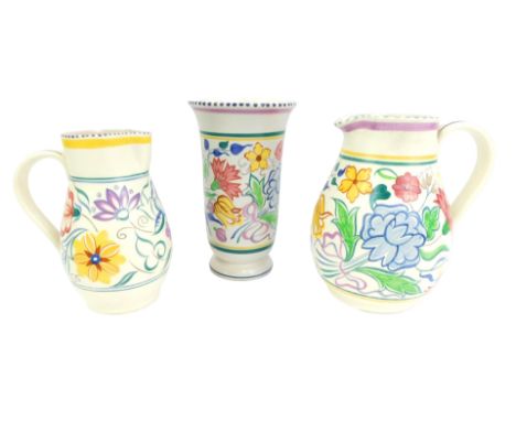 Three items of Poole pottery, traditionally decorated with floral sprays, comprising two jugs, 20cm high and 18.5cm high, and