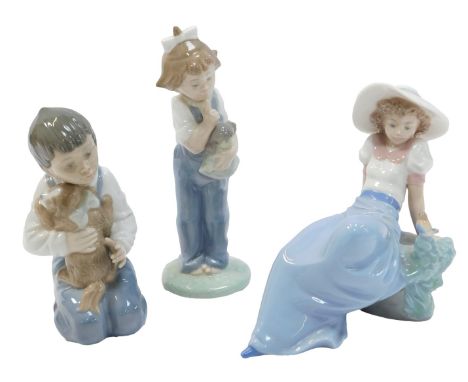 Thee Nao porcelain figures, modelled as a young girl holding doll, 19cm high, a boy kneeling holding puppy, 15cm high, a youn