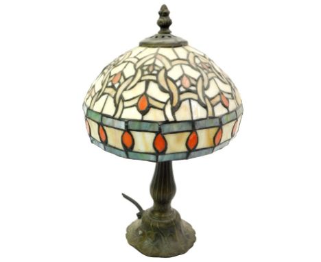 A Tiffany style table lamp, with a circular opalescent glass shade, raised on a fluted stem and swept foot, decorated with fl