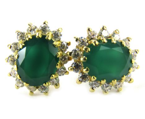 A pair of emerald and diamond cluster earrings, the oval emerald in a claw setting, surrounded by tiny diamonds, the yellow m